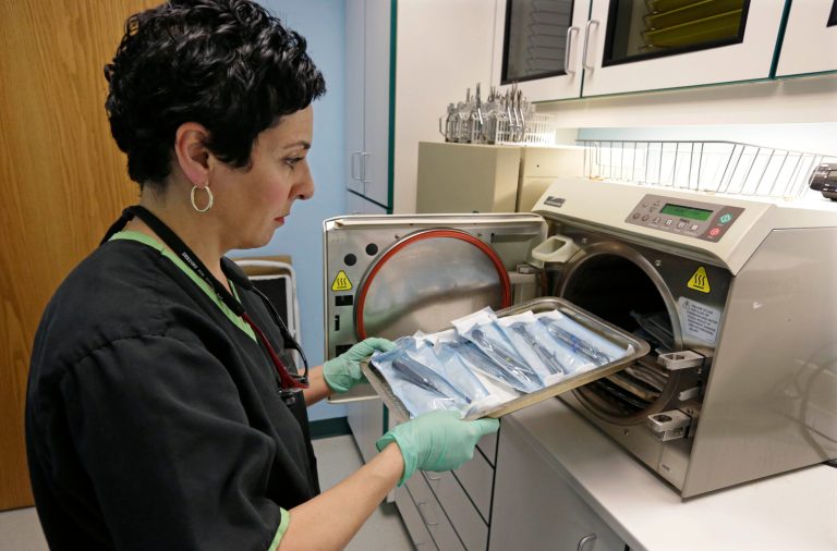 Dentist Alice G. Boghosian removes packages of properly sterilized dental instruments from an autoclave that uses heat and steam to sterilize the tools Friday, March 29, 2013, in Chicago. Health officials in Oklahoma are calling an oral surgeon there who used dirty equipment and risked cross-contamination a 