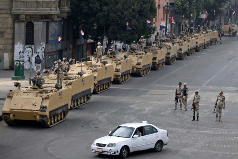 In this Friday, Aug. 16, 2013 photo, Egyptian army soldiers take their positions on top and next to their armored vehicles to guard an entrance of Tahrir square, in Cairo, Egypt. Egypt's capital has long been proud of its nickname, 