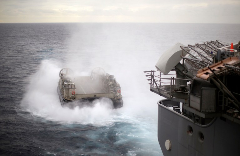 An U.S. Navy Landing Craft Air Cushion (LCAC) appears from the stern of the USS Bonhomme Richard amphibious assault ship and heads towards Sydney, Australia, Thursday, July 29, 2017, during events marking the start of Talisman Saber 2017, a biennial joint military exercise between the United States and Australia. (Jason Reed/Pool via AP)