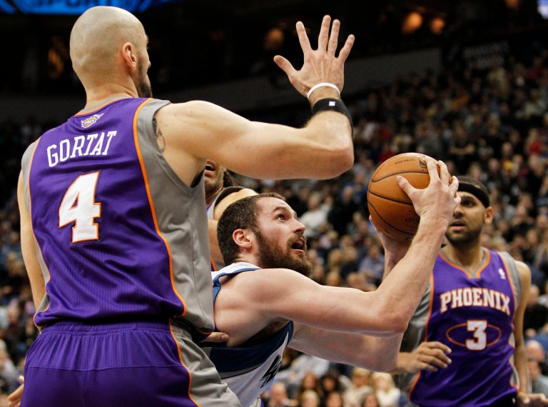   Minnesota Timberwolves forward Kevin Love, center, is fouled on his way to the basket by Phoenix Suns center Marcin Gortat (4) as Suns guard Jared Dudley (3) looks on during the first half of an NBA basketball game, Saturday, Dec. 29, 2012, in Minneapolis. (AP Photo/Genevieve Ross)  