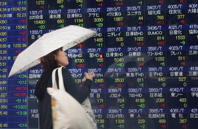 A woman looks at an electronic stock indicator of a securities firm in the rain in Tokyo, Friday, June 6, 2014. Asian stocks were mostly indifferent on Friday to the unveiling of a big stimulus package from the European Central Bank as investors awaited the U.S. jobs report for May. (AP Photo/Eugene Hoshiko)