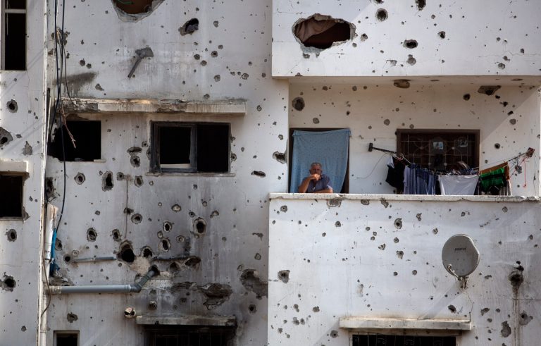 A Palestinian man stands on the balcony of his destroyed house as he waits for the visit of Palestinian Prime Minister Rami Hamdallah to Gaza's neighborhood of Shijaeyih, Thursday, Oct. 9, 2014. Members of the new Palestinian unity government assembled in Gaza on Thursday for their first Cabinet session in the war-battered territory - a largely symbolic meeting meant to mark the end of absolute Hamas control of the coastal strip. (AP Photo/Khalil Hamra)