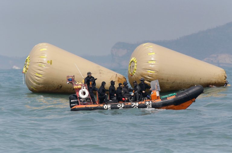South Korean rescue team members work to rescue passengers believed to have been trapped in the sunken ferry Sewol near the buoys which were installed to mark the vessel in the water off the southern coast near Jindo, south of Seoul, South Korea, Sunday, April 20, 2014. After more than three days of frustration and failure, divers on Sunday finally found a way into the submerged ferry off South Korea's southern shore, discovering more than a dozen bodies inside the ship and pushing the confirmed death toll to over four dozen, officials said. (AP Photo/Lee Jin-man)