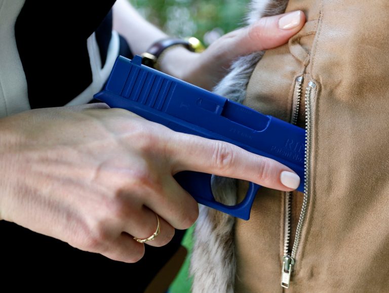Marilyn Smolenski uses a mock gun to demonstrate how to pull a handgun out of the concealed carry clothing she designs at her home in Park Ridge, Ill. Interest in clothing that allow women to carry a firearm concealed is rising. Pioneers in the industry say they allow women to avoid looking frumpy and still carry a firearm safely and effectively. (AP Photo/Tae-Gyun Kim)