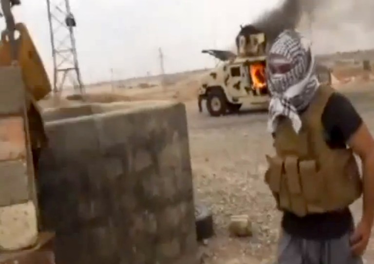 A group supporting the al-Qaida breakaway Islamic State of Iraq and the Levant (ISIL) on Wednesday, June 11, 2014, which has been verified and is consistent with other AP reporting, shows a militant standing in front of a burning Iraqi Army Humvee in Tikrit, Iraq. The al-Qaida-inspired group that led the charge in capturing two key Sunni-dominated cities in Iraq this week has vowed to march on to Baghdad, raising fears about the Shiite-led governmentâs ability to slow the assault following lightening gains. Fighters from ISIL on Wednesday took Saddam Hussein's hometown of Tikrit, as soldiers and security forces abandoned their posts and yielded ground once controlled by U.S. forces. (AP Photo/Iraqi0Revolution via AP video)