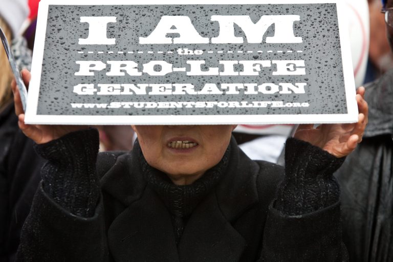 WASHINGTON, DC - JANUARY 23: A woman shields herself from the rain at the March for Life rally on January 23, 2012 in Washington, DC. Pro-life activists gather each year to protest on the anniversary of the Roe v. Wade Supreme Court decision that legalized abortion. (Photo by Brendan Hoffman/Getty Images)
