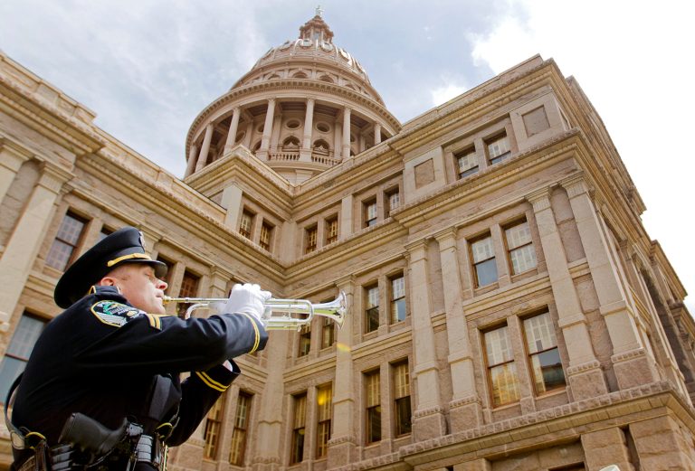 An officer plays Taps on the Texas State Capitol steps in Austin, Texas. (AP Photo/Statesman.com, Ricardo Brazziell)