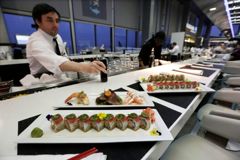   In this photo taken Tuesday, Dec. 18, 2012, at O'Hare International Airport in Chicago, a waiter delivers plates of fresh sushi at Wicker Park Seafood & Sushi in Terminal 2. Getting stranded at an airport once meant camping on the floor and enduring hours of boredom in a kind of travel purgatory with nothing to eat but fast food. Tough economic times are helping drive airports to make amends and transform terminals with a bit of bliss: spas, yoga studios, luxury shopping and restaurant menus crafted by celebrity chefs. (AP Photo/M. Spencer Green)  