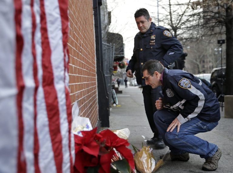 Police officers leave candles at an impromptu memorial near the site where two New York City police officers were killed in the Brooklyn borough of New York, Sunday, Dec. 21, 2014. (AP Photo/Seth Wenig)