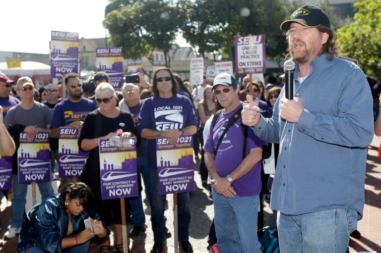 Chris Finn, right, a 17-year BART train operator and union official, speaks at a workers' rally on Friday in Oakland, Calif. (AP Photo/Marcio Jose Sanchez)