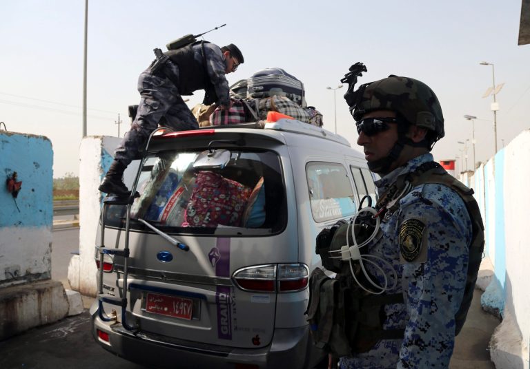 An Iraqi federal policeman stands guard as his colleague searches a car at a checkpoint in Baghdad, Iraq, Saturday. On the western edge of Iraq's capital, Islamic State group militants battle government forces and exchange mortar fire, only adding to the sense of siege in Baghdad despite airstrikes by a U.S.-led coalition. Military experts say the Sunni militants, won't be able to fight through both government forces and Shiite militias now massed around the capital, It does, however, put them in a position to wreak havoc in Iraq's biggest city, with its suicide attacks and other assaults. (AP Photo/Karim Kadim)