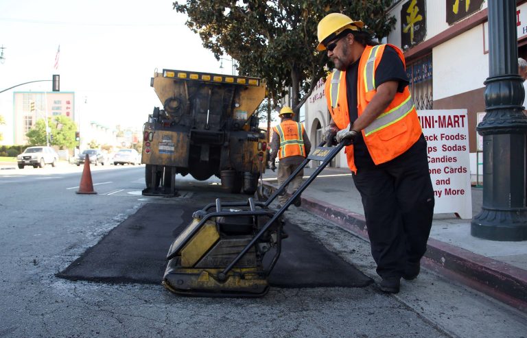 Los Angeles city worker Ralph Mendoza repairs a street in downtown Los Angeles on Thursday, Sept. 11, 2014. Poorly maintained highways and major roads cost Californians an extra $44 billion each year in repairs, accidents and time and fuel burned in traffic, according to a report issued Thursday by a transportation advocacy group. (AP Photo/Nick Ut)