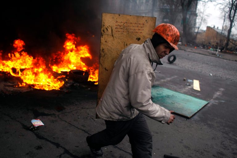 An anti-government protester carries a shield as he runs on the outskirts of Independence Square in Kiev, Ukraine, on Thursday. (AP/Marko Drobnjakovic)