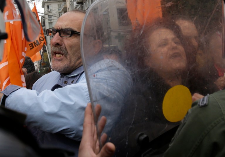Protesters scuffle with riot police outside the Finance Ministry during a rally in Athens, on Friday, Feb. 28, 2014. Hundreds of teachers, municipality workers, school guards and cleaning women who have been suspended on reduced pay pending transfer to other public sector jobs or dismissal, took part in the protest as the officials from the European Union, European Central Bank and International Monetary Fund, together known as the troika, were holding talks with the Minister of Administration Reform Kyriakos Mitsotakis  and other government officials. (AP Photo/Thanassis Stavrakis)