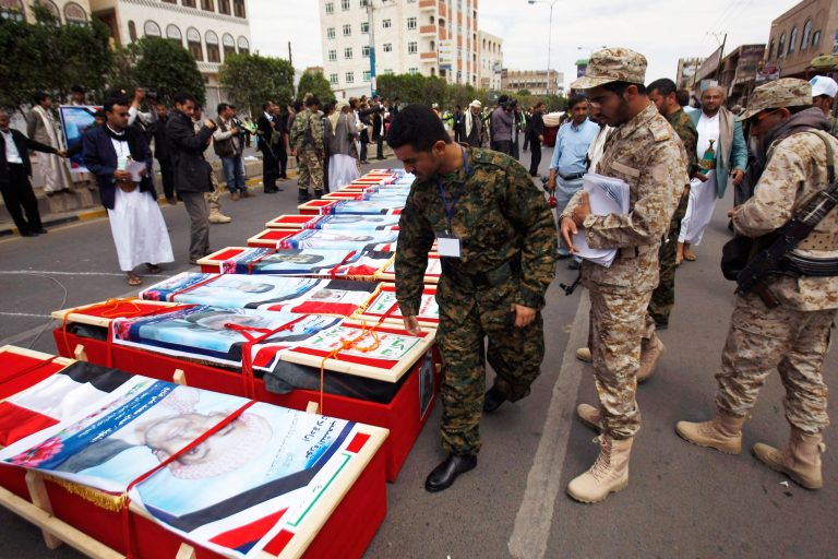 Houthi Shiite Yemenis wearing an army uniforms,  stand near the coffins of a men who were killed last Thursday by a suicide bomber in central Sanaa, Yemen, Tuesday, Oct. 14, 2014. Two suicide bombings in Yemen killed nearly 70 people last Thursday, with one targeting an anti-government rally by followers of the Houthi Shiite group, who control Sanaa. (AP Photo/Hani Mohammed)