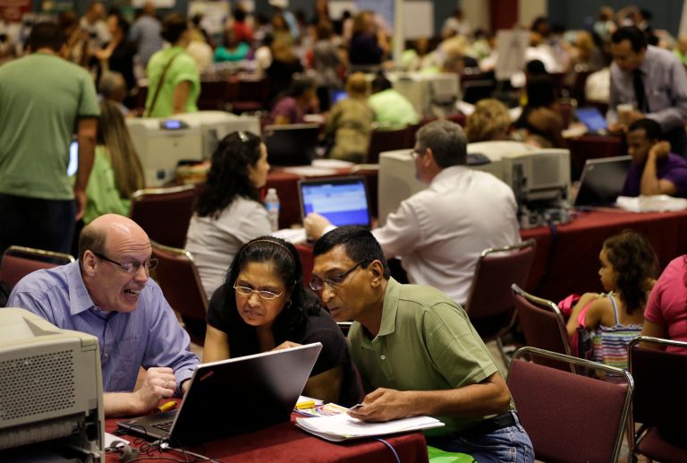 FILE - In this Sept. 3, 2014 file photo, former Revel Hotel Casino employees, Jignasha Shah, 45, center, and Ranjitsinh Rana, 56, right, get help from John McCaffery, as they and thousands of other newly laid-off casino workers file for unemployment benefits at the Atlantic City Convention Center in Atlantic City, N.J. The government reports on state unemployment rates for August on Friday, Sept. 19, 2014. (AP Photo/Mel Evans, File)