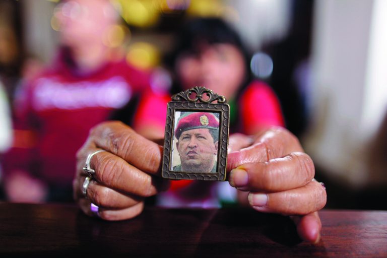 A woman holds an image of Venezuela's President Hugo Chavez as people gather to pray for him at a church in Caracas, Venezuela, Monday, Dec. 31, 2012. Venezuela's President Hugo Chavez is confronting 