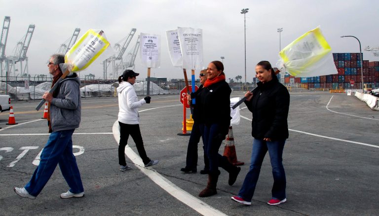   Clerical workers carry signs in protest at the Port of Long Beach, Calif. on Tuesday, December 4, 2012. Los Angeles Mayor Antonio Villaraigosa says both sides in a strike at the twin ports of Los Angeles and Long Beach have agreed to federal mediation. However, the union representing clerical workers says the strike now in its eighth day will continue. Clerical workers are striking 10 terminals at the nation's busiest port complex and dockworkers won't cross picket lines. (AP Photo/Nick Ut)  