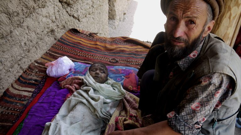 An Afghan man sits by the body of his son after flooding in the northeastern Baghlan province, north of Kabul, Afghanistan, Saturday, June 7, 2014. Flooding in a remote part of northern Afghanistan has claimed more than 50 lives and forced thousands to flee their homes, a provincial official said Saturday. (AP Photo/Javid Basharat)