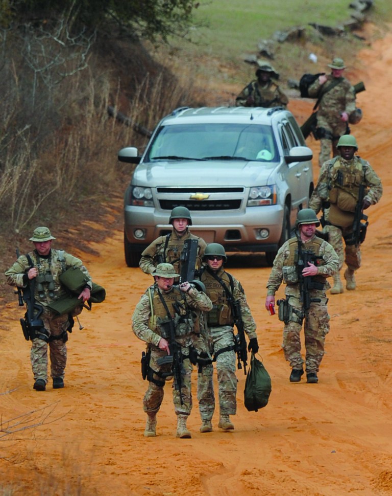 Heavily armed men come back down the hill from the direction of the suspect's home at the Dale County hostage scene near Midland City, Ala. on Wednesday Jan. 30, 2013. Police SWAT teams and hostage negotiators were locked in a standoff Wednesday with a gunman authorities say intercepted a school bus, killed the driver, snatched a 6-year-old boy and retreated into a bunker at his home. (AP Photo/Montgomery Advertiser, Mickey Welsh) NO SALES