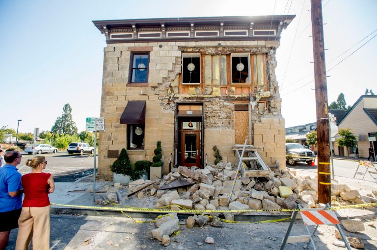 FILE - In this Aug. 24, 2014, file photo, pedestrians examine a crumbling facade following an earthquake at the Vintner's Collective tasting room in Napa, Calif. Four long fault segments running beneath northern California and its roughly 15 million people all have become locked far underground, and loaded with enough tension to produce earthquakes of magnitude 6.8 or greater, a geological study published Monday, Oct. 13, 2014 says. (AP Photo/Noah Berger, File)