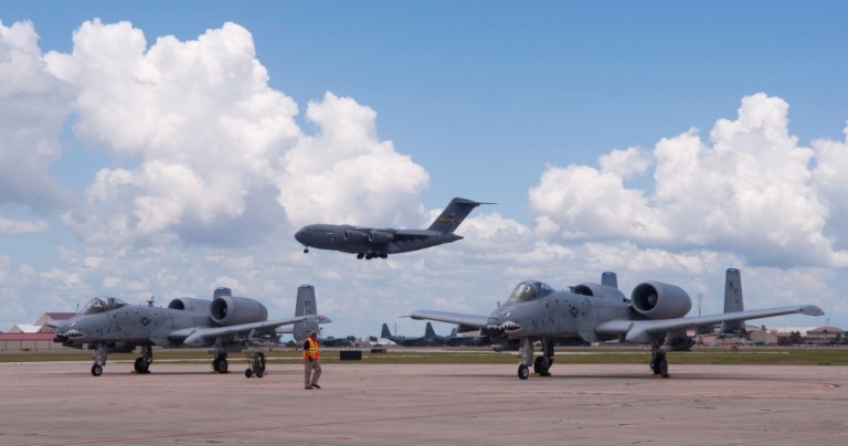 Two A-10C Thunderbolt II's wait for take-off as a C-17 Globemaster III flies overhead at Patrick Air Force Base, Fla., July 16, 2019. 