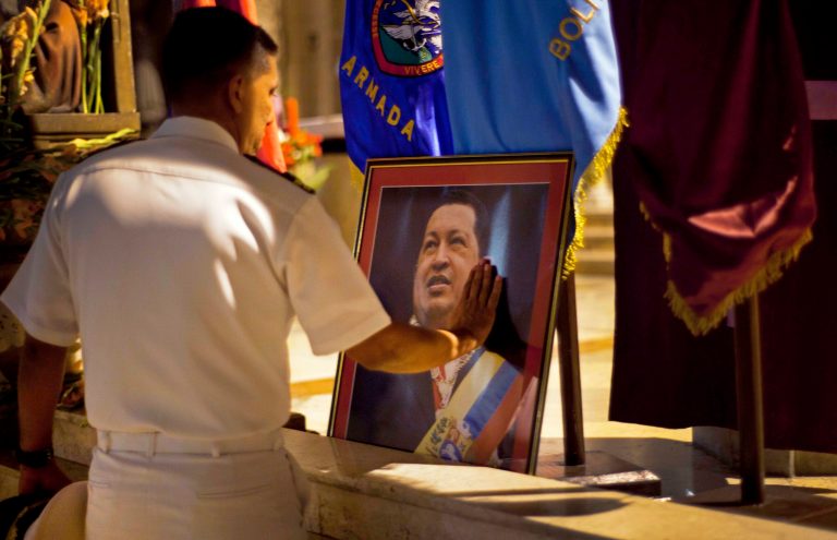   FILE - In this Thursday, Dec. 13, 2012 file photo, a member of Venezuela's navy touches an image of Venezuela's President Hugo Chavez after a mass in support of him in Havana, Cuba. Venezuelan Vice President Nicolas Maduro said late Monday, Dec. 24, 2012 night that he had spoken by telephone with Chavez and that the leader is up and walking following cancer surgery in Cuba. (AP Photo/Ramon Espinosa)  