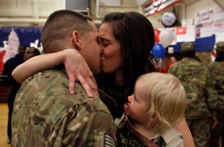   In this Nov. 30, 2012. photo, U.S. Army 1st Lt. Aaron Dunn kisses his wife Leanne, holding their baby Emma, age 14 months, as they reunite during an arrival ceremony for soldiers returning from a deployment in Afghanistan, at Ft. Carson, in Colorado Springs, Colo. 1st Lt. Dunn, with the 4th Brigade Combat Team, 4th Infantry Division, had not seen his wife and baby since he deployed in March. (AP Photo/Brennan Linsley)  