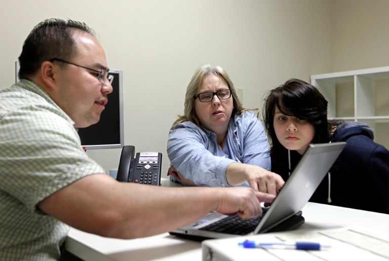 In this Feb. 12, 2015, file photo, Enrollment counselor Vue Yang, left, goes over some of the health insurance plans available to Laura San Nicolas, center, accompanied by her daughter, Geena, 17, while enrolling for health insurance at Sacramento Covered in Sacramento, Calif. (AP Photo/Rich Pedroncelli, File)