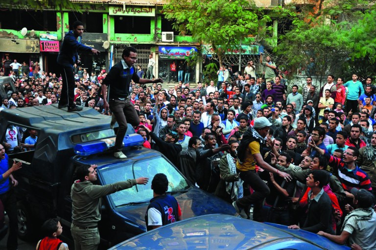 Egyptians stand on police vehicles during the funeral of Gaber Salah, who was who was killed in clashes with security forces in Cairo, Egypt, Monday, Nov. 26, 2012. Thousands of Egyptians on Monday gathered into Cairo's Tahrir Square to attend the funeral of Salah, who was severely injured during clashes with security forces last week and died Sunday night. (AP Photo/Hussein Tallal)