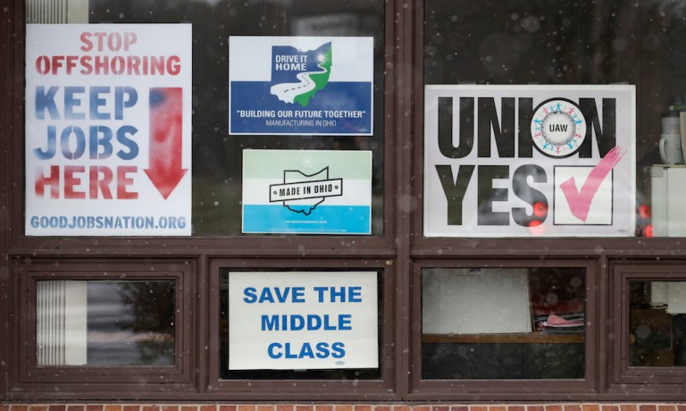 Signs hang from windows at the UAW Local 1112 union hall, Tuesday, Nov. 27, 2018, in Lordstown, Ohio. Even though unemployment is low, the economy is growing and U.S. auto sales are near historic highs, GM is cutting thousands of jobs in a major restructuring aimed at generating cash to spend on innovation. GM put five plants up for possible closure, including the plant in Lordstown.