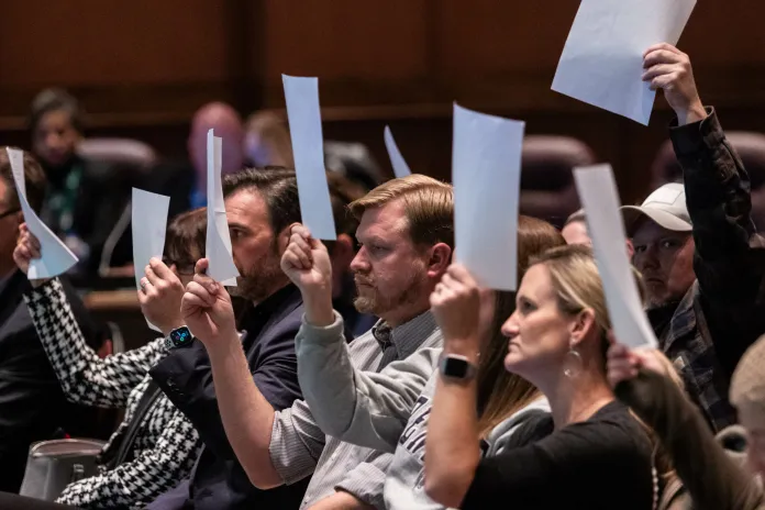 Parents hold up blank pieces of paper in a sign of protest at the Dec. 13, 2022, Loudoun County School Board meeting.