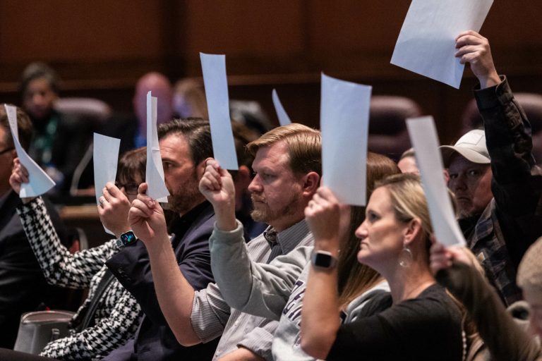 Parents hold up blank pieces of paper in a sign of protest at the Dec. 13, 2022, Loudoun County School Board meeting.