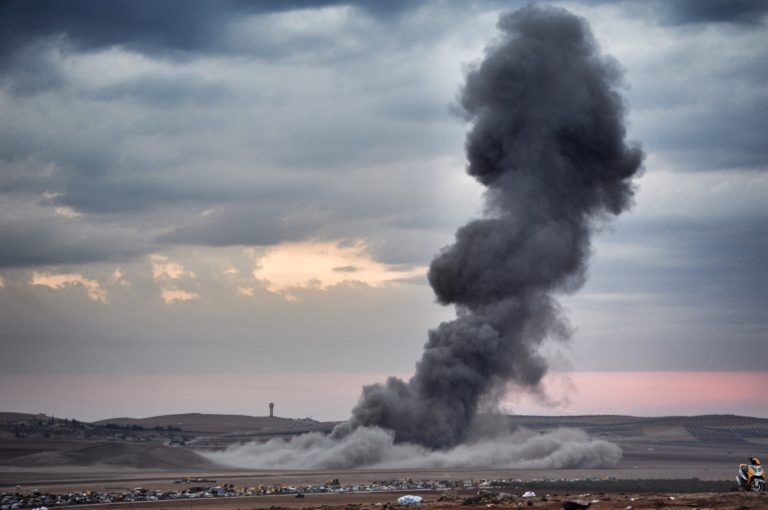 Smoke and dust rise over Syrian town of Kobani after an airstrike, as seen from the Mursitpinar crossing on the Turkish-Syrian border in the southeastern town of Suruc in Sanliurfa province, October 23, 2014. (Photo by Kutluhan Cucel/Getty Images)