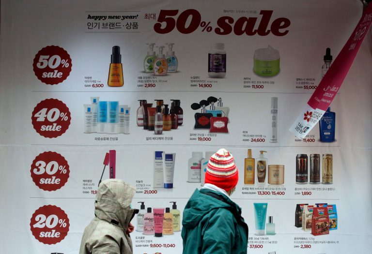 Visitors look at a sale advertisement in downtown Seoul, South Korea, Thursday, Jan. 23, 2014. South Korea's economy recorded its fastest quarterly growth since the first quarter of 2011, its central bank said Thursday, showing Asia's fourth-largest economy is on track to recovery. (AP Photo/Lee Jin-man)