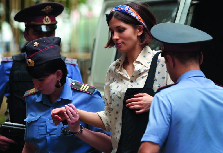Nadezhda Tolokonnikova, centre, a member of feminist punk group Pussy Riot is escorted to a court room in Moscow, Russia, Tuesday, Aug. 7, 2012. Russia's President Vladimir Putin on Thursday criticized the feminist punk rockers facing trial for performing a 