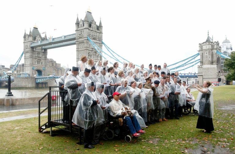 The Military Wives choir along with other SSAFA beneficiaries brave the rain during a launch event for their new recording of 'Pack Up Your Troubles', proceeds of which will benefit charitable organisation SSAFA, at South Bank, London, Sunday, Aug. 10, 2014. (AP Photo/Jonathan Brady, PA Wire)    UNITED KINGDOM OUT   -   NO SALES    -    NO ARCHIVES
