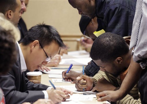 In this Wednesday, Feb. 6, 2013 photo, job applicants, right, complete forms at a job fair sponsored by Swissport, in Newark N.J. The Labor Department reports Thursday, Feb. 7, 2013, on the number of Americans who applied for unemployment benefits for the first time in the last week. (AP Photo/Mark Lennihan)