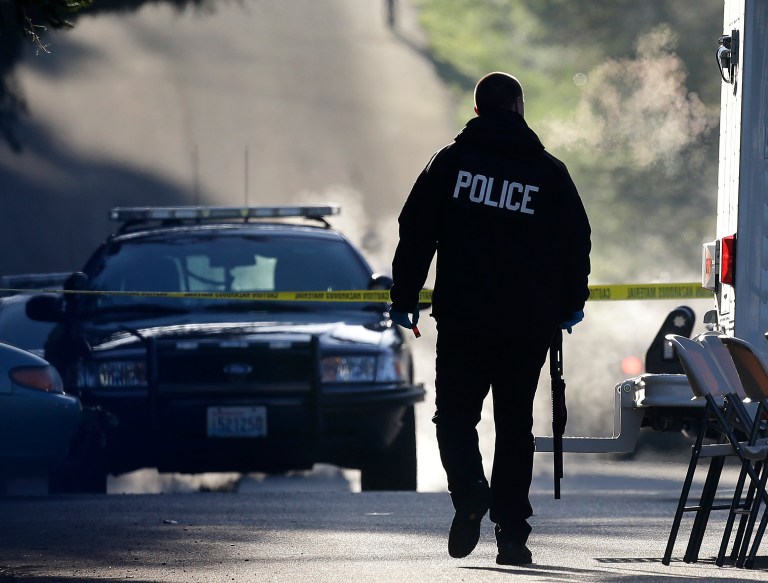 A police officer carries a shotgun and what appears to be a shell casing as officers collect evidence from the scene of an overnight shooting that left five people dead, including a suspect who was shot by arriving officers, at an apartment complex in Federal Way, Wash., early Monday, April 22, 2013. Federal Way Police Cmdr. Kyle Sumpter confirmed Monday that the shotgun pictured was used by the suspect in the shooting. (AP Photo/Ted S. Warren)
