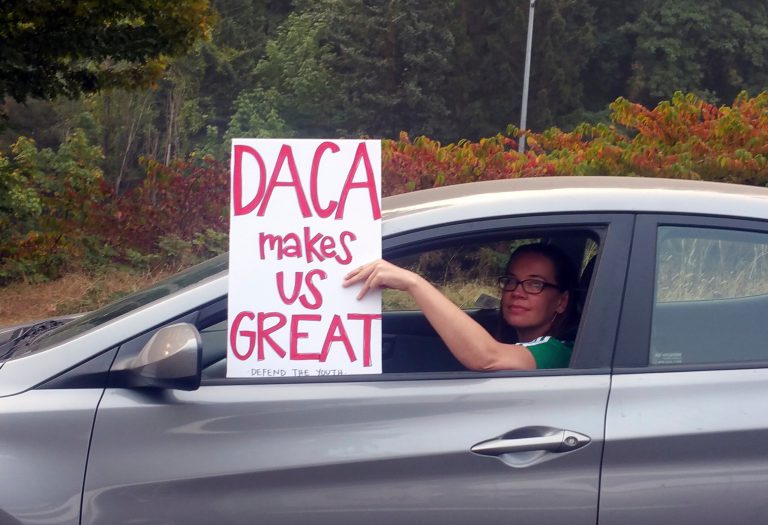 An unidentified woman holds a sign out her window as she drives through rush hour traffic in Portland, Ore., Tuesday, Sept. 5, 2017. President Donald Trump on Tuesday began dismantling the Deferred Action for Childhood Arrivals, or DACA, program, the government program protecting hundreds of thousands of young immigrants who were brought into the country illegally as children. (AP Photo/Don Ryan)