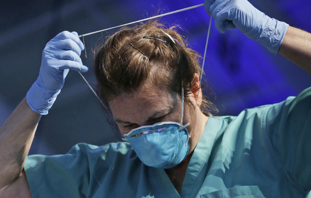Nurse Barbara Smith demonstrates the proper way to remove some personal protective equipment when dealing with Ebola during an education session in New York, Tuesday, Oct. 21, 2014. (AP Photo/Seth Wenig)