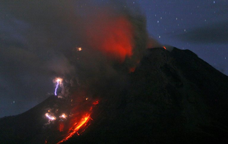 In this late Monday, Oct. 13, 2014 photo made with a slow shutter speed, lightning caused by volcanic materials containing electric charges that collide into each other is seen as Mount Sinabung erupts in Jeraya, North Sumatra, Indonesia. Mount Sinabung, among about 130 active volcanoes in Indonesia, has sporadically erupted since 2010 after being dormant for 400 years. (AP Photo/Binsar Bakkara)