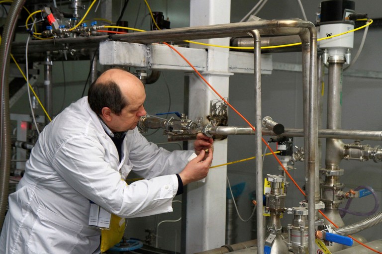 An unidentified International Atomic Energy Agency inspector cuts the connections between the twin cascades for 20 percent uranium enrichment at the Natanz facility, some 200 miles south of the capital Tehran, Iran, Monday, Jan. 20, 2014. (AP Photo/IRNA, Kazem Ghane)