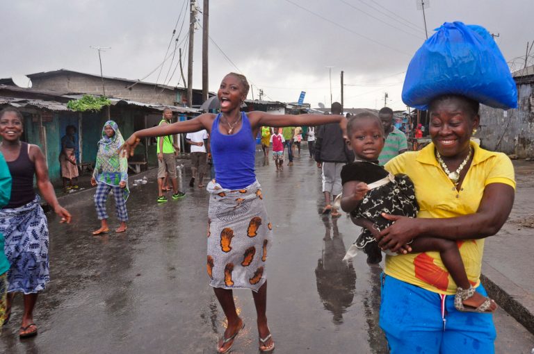 A woman, center,  reacts as she and others celebrate on the streets outside of West Point, that have been closed in by Liberian security forces to stop all movement the past week in a attempt to control the Ebola outbreak in Monrovia, Liberia, Saturday, Aug. 30, 2014. Liberia says it will open up a slum in its capital where thousands of people were barricaded to contain the spread of Ebola. Information Minister Lewis Brown says lifting the quarantine Saturday morning will not mean there is no Ebola in the West Point Slum. (AP Photo/Abbas Dulleh)