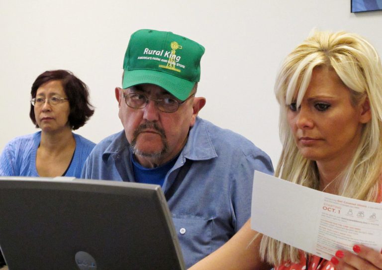 Patrick Lamanske of Champaign, Ill., works with Amanda Ziemnisky, right, of the Champaign Urbana Public Health District office to try to sign his wife, Ping Lamanske, left, up for healthcare coverage through the Affordable Care Act. (AP Photo)