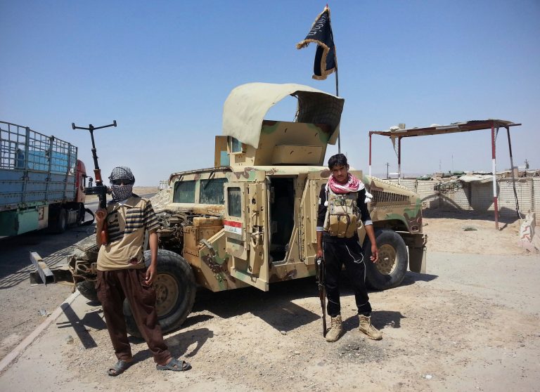 Al Qaeda-inspired militants stand with captured Iraqi Army Humvee at a checkpoint outside Beiji refinery, some 155 miles north of Baghdad, in this file photo taken Thursday, June 19, 2014. (AP Photo, File)