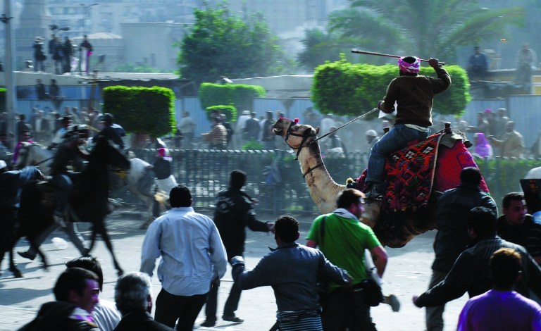 FILE - In this Wednesday, Feb. 2, 2011 file photo, supporters of President Hosni Mubarak, riding camels and horses, fight with anti-Mubarak protesters in Cairo, Egypt. Ousted President Hosni Mubarak watched the uprising against him unfold through a live TV feed, despite his earlier denial that he knew the extent of the protests and violence, according to a fact-finding mission member said Wednesday, Jan. 2, 2013, which could lead to the retrial of the 84-old ousted leader already serving a life sentence.(AP Photo/Mohammed Abu Zaid, File)