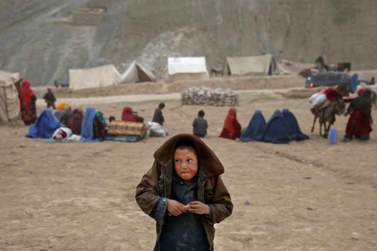In this Sunday, May 4, 2014 photo, an Afghan child protects himself from the rain, near the site of Friday's landslide that buried Abi-Barik village in Badakhshan province, northeastern Afghanistan. Stranded and with no homes, many of the families have struggled to get aid. Some have gone to nearby villages to stay with relatives or friends, while others have slept in tents provided by aid groups. The unlucky ones have slept outside. (AP Photo/Massoud Hossaini)
