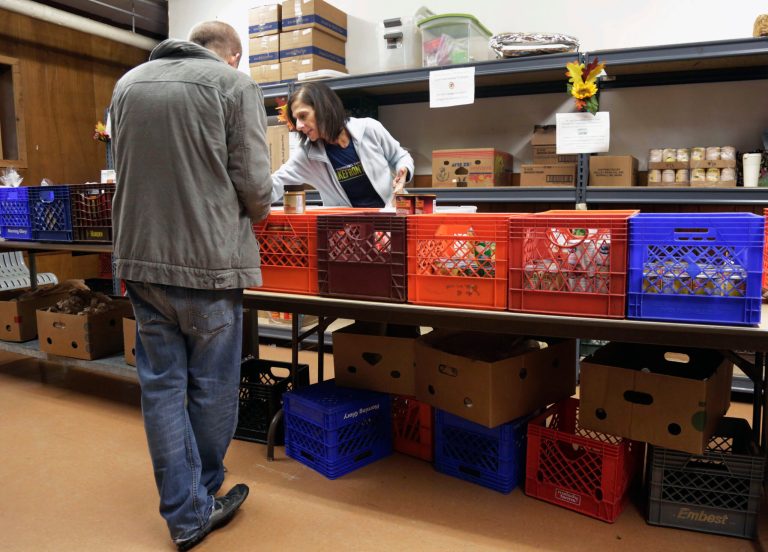 In this Nov. 1, 2013 file photo, a volunteer at right helps a customer at the St. Ignatius Food Pantry in Chicago. According to a report released Thursday, Jan. 30, 2014, by the Chicago-based Social IMPACT Research Center, the overall Illinois poverty rate is the same as it was a half century ago, despite scores of state and federal aid programs and a dramatic drop in the number of elderly considered poor. (AP Photo/M. Spencer Green, File)