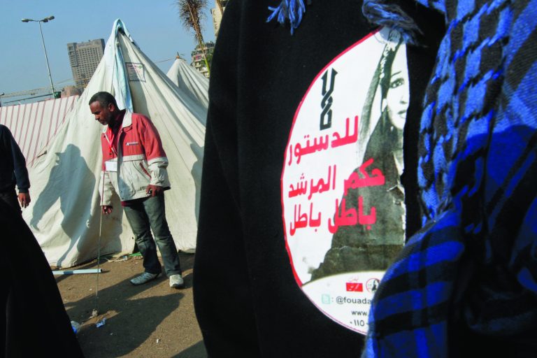 A protesters wears a sticker with Arabic that reads, 